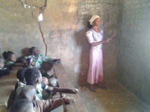 One of the teachers on duty behind cracked walls as the    children listen