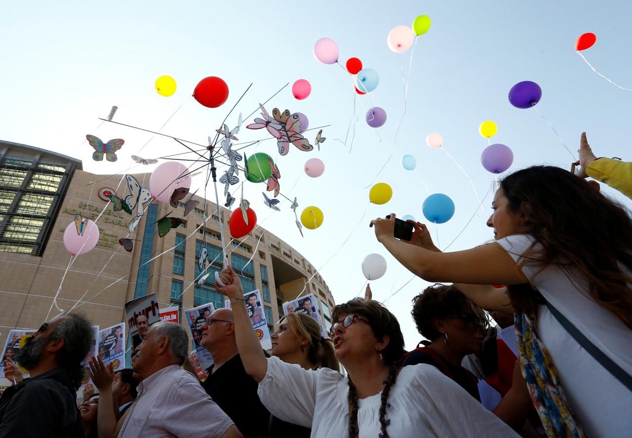 Journalists and press freedom activists release balloons during a demonstration in solidarity with the members of the opposition newspaper Cumhuriyet who were accused of supporting a terrorist group outside a courthouse, in Istanbul