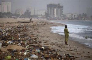 A man stands on the shore of Bar Beach, awash with rubbish and waste, in Lagos