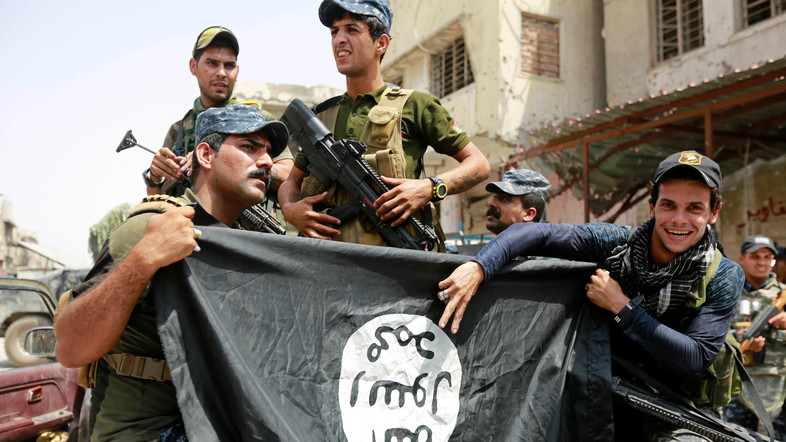 Iraqi Federal Police members hold an Islamic State flag, which they pulled down during fighting between Iraqi forces and Islamic State militants, in the Old City of Mosul