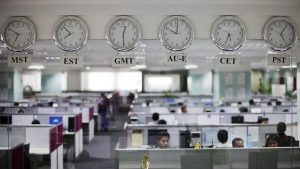 Workers are pictured beneath clocks displaying time zones in various parts of the world at an outsourcing centre in Bangalore