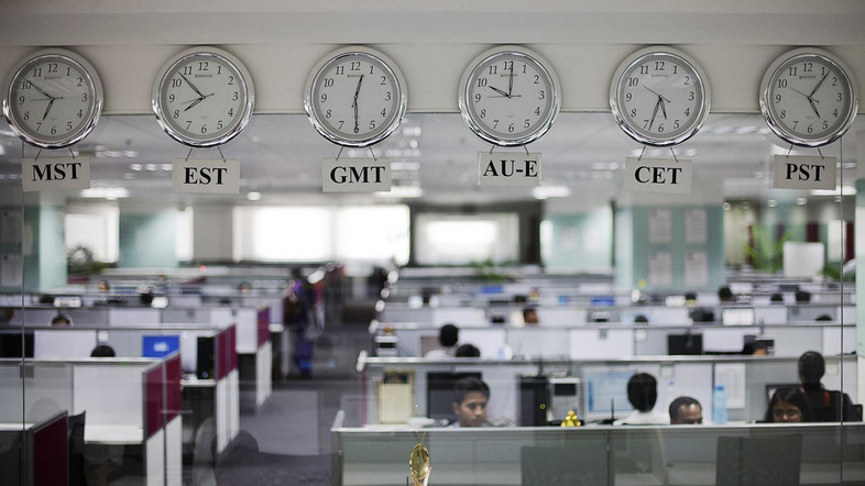 Workers are pictured beneath clocks displaying time zones in various parts of the world at an outsourcing centre in Bangalore