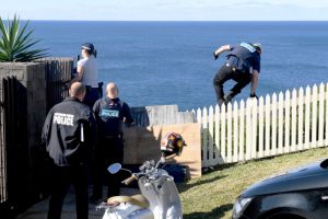 A policeman jumps a fence at the home of John Ibrahim during a police operation in Sydney