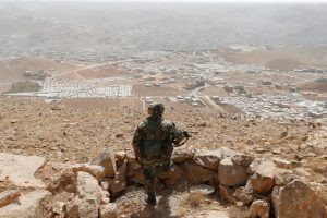 FILE PHOTO: A Lebanese soldier carries his weapon as he stands on sandbags at an army post in the hills above the Lebanese town of Arsal, near the border with Syria