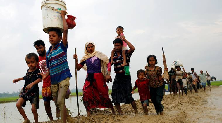 Rohingya refugees walk on the muddy path after crossing the Bangladesh-Myanmar border in Teknaf
