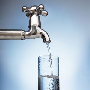 Light gray tap pours down water into glass