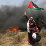 Woman demonstrator holds a Palestinian flag during clashes with Israeli troops at a protest where Palestinians demand the right to return to their homeland, at the Israel-Gaza border in the southern Gaza Strip