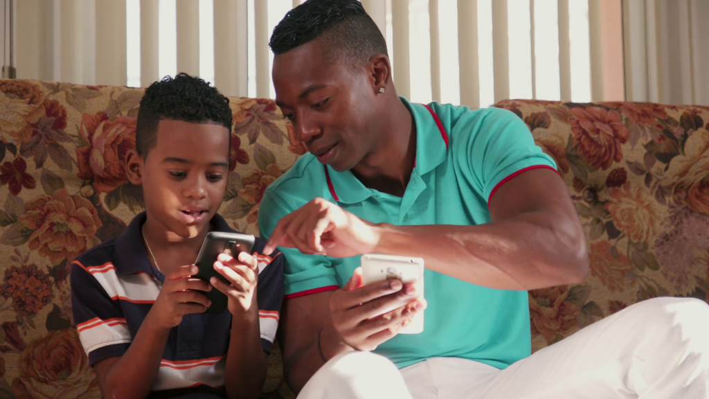 black-man-teaching-mobile-telephone-technology-to-boy-at-home_b0mpgdukl_thumbnail-full01