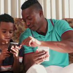black-man-teaching-mobile-telephone-technology-to-boy-at-home_b0mpgdukl_thumbnail-full01