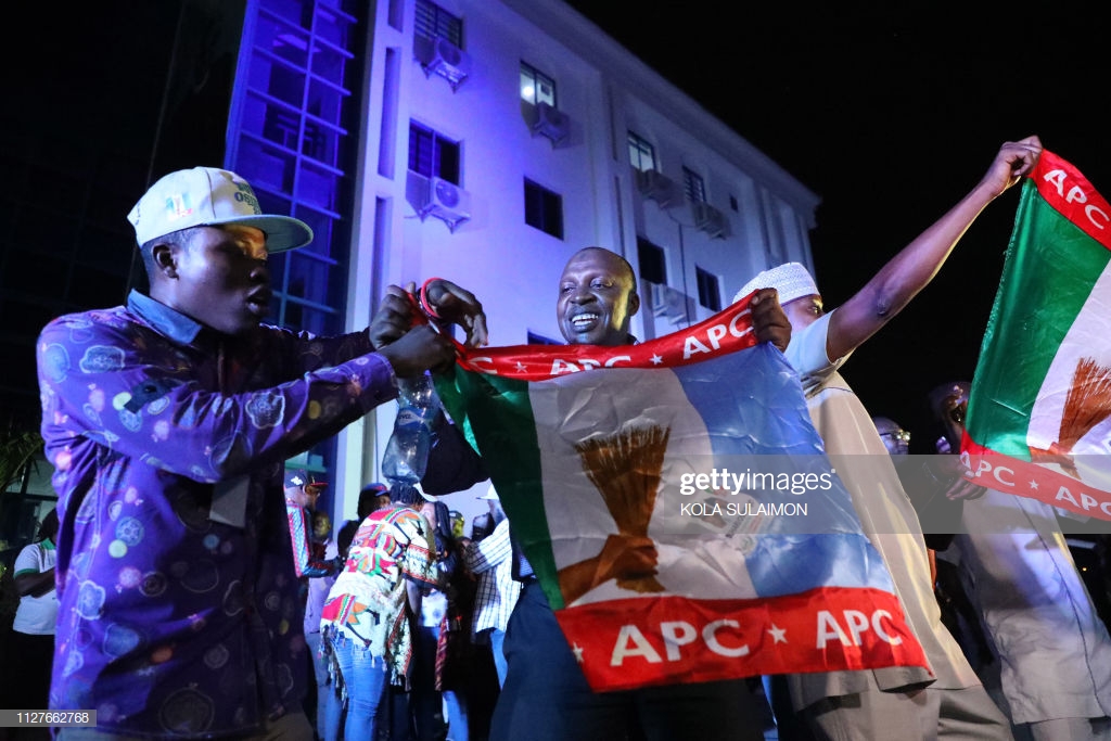 Supporters of the ruling APC celebrate with party flags in Abuja after candidate President Mohammadu Buhari was re-elected on February 26, 2019 (Photo credit: KOLA SULAIMON/AFP/Getty Images)