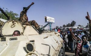 A-sudanese-soldier-gives-the-power-salute-as-protesters-mass-around-the-defense-ministry-complex-e1554965720507