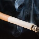 lit cigarette on black background with smoke