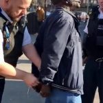 Mr-Ilesanmi-Oluwole-and-being-handcuffed-by-a-Metropolitan-Policeman