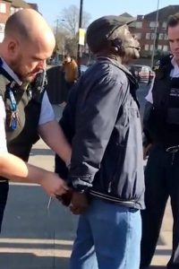 Mr-Ilesanmi-Oluwole-and-being-handcuffed-by-a-Metropolitan-Policeman