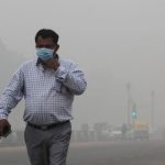 A man wearing a mask walks on a smoggy morning in New Delhi