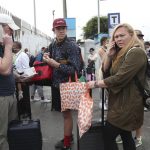Tourists from the United States wait outside the closed Jorge Chavez International Airport for a member of the U.S. Embassy to escort them to a flight that will fly them back to the U.S., in Callao Peru, Friday, March 20, 2020, on the fifth day of a state of emergency decreed by the government to prevent the spread of the new coronavirus. (AP Photo/Martin Mejia)