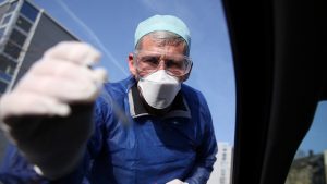 German doctor Michael Grosse takes a sample from a car driver through the window on March 27, 2020 at a drive through testing point for the novel coronavirus on a parking in Halle, eastern Germany. (Photo by Ronny Hartmann / AFP)