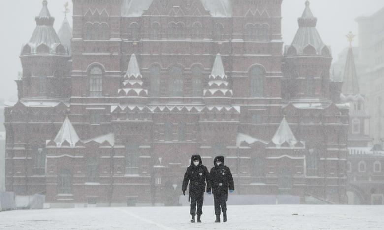 Police officers cross an empty Red Square in Moscow, Russia. The Russian capital woke up to a lockdown in response to coronavirus, obliging most people in the city of 13 million to stay home. Photograph: Pavel Golovkin/AP