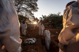 Workers wearing protective equipment prepare to bury the casket of a Covid-19 victim at the Vila Formosa cemetery in Sao Paulo, Brazil, on May 29. Photographer: Jonne Roriz/Bloomberg