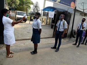 A health worker checks the temperature with an infrared thermometer of students queueing and keeping distances on resumption of studies at Access International Schools, in Magboro, Ogun State, southwest Nigeria, on Aug. 4, 2020. PHOTO BY PIUS UTOMI EKPEI/AFP VIA GETTY IMAGES