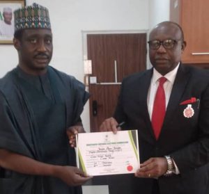 Rt Hon Jarigbe, left, receiving the CoR from Festis Okoye, right, INEC Commissioner in charge of Information and Voter Education