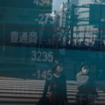 People wearing protective face masks, following an outbreak of the coronavirus, are reflected on a screen showing Nikkei index, outside a brokerage in Tokyo, Japan Feb. 28, 2020. (Reuters file photo)