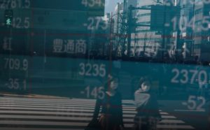 People wearing protective face masks, following an outbreak of the coronavirus, are reflected on a screen showing Nikkei index, outside a brokerage in Tokyo, Japan Feb. 28, 2020. (Reuters file photo)