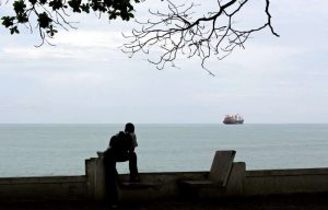 a-man-sitting-on-a-bench-next-to-a-body-of-water-the-gulf-of-guinea-is-the-most-dangerous-sea-in-the_224978_