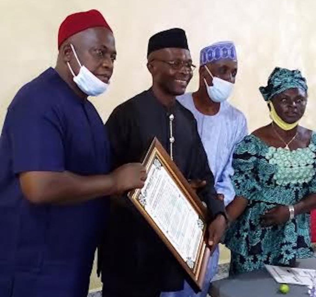 Chief displays his BoT membership certificate with NANFACOS executive in Nnewi