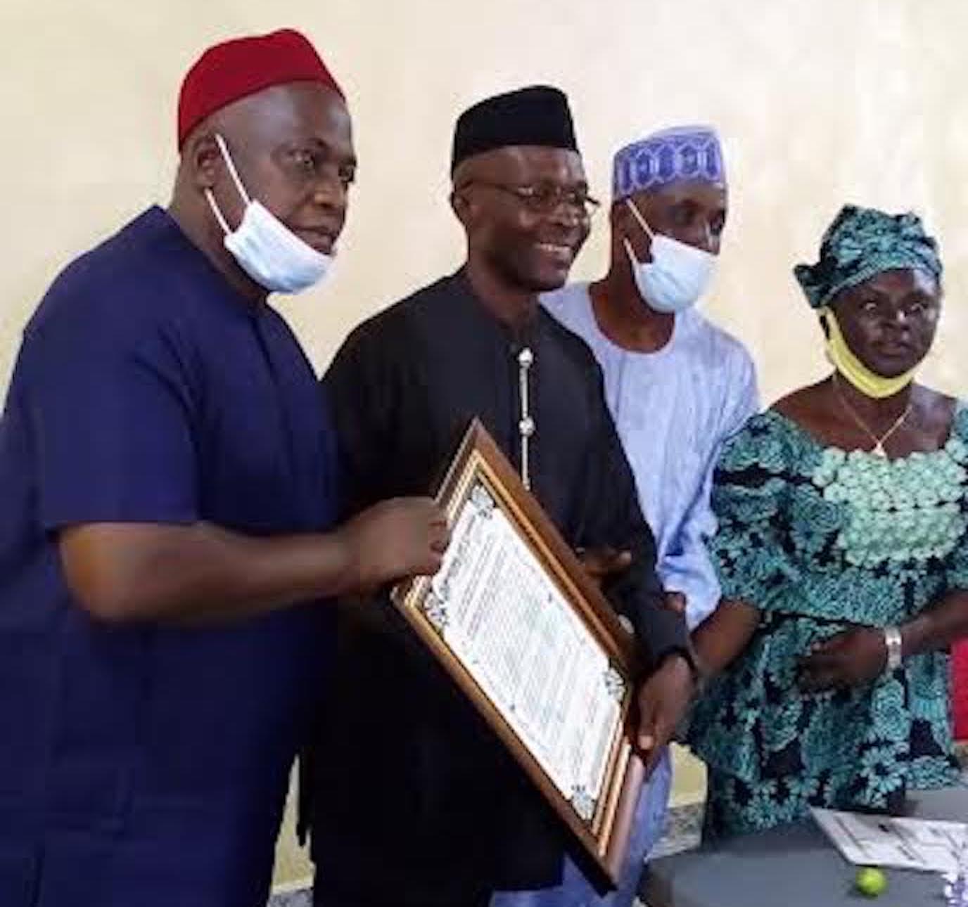 Chief displays his BoT membership certificate with NANFACOS executive in Nnewi
