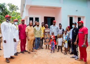 The benefactor and friends posing with the beneficiary infront of the new house
