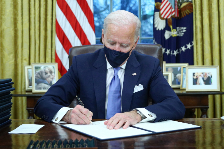President Joe Biden signs executive orders inside the Oval Office at the White House in Washington