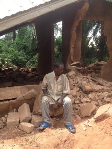 Anibueze seated in front of his demolished house