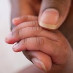 close up of an african american baby hand in mother’s hand