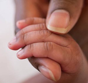 close up of an african american baby hand in mother’s hand