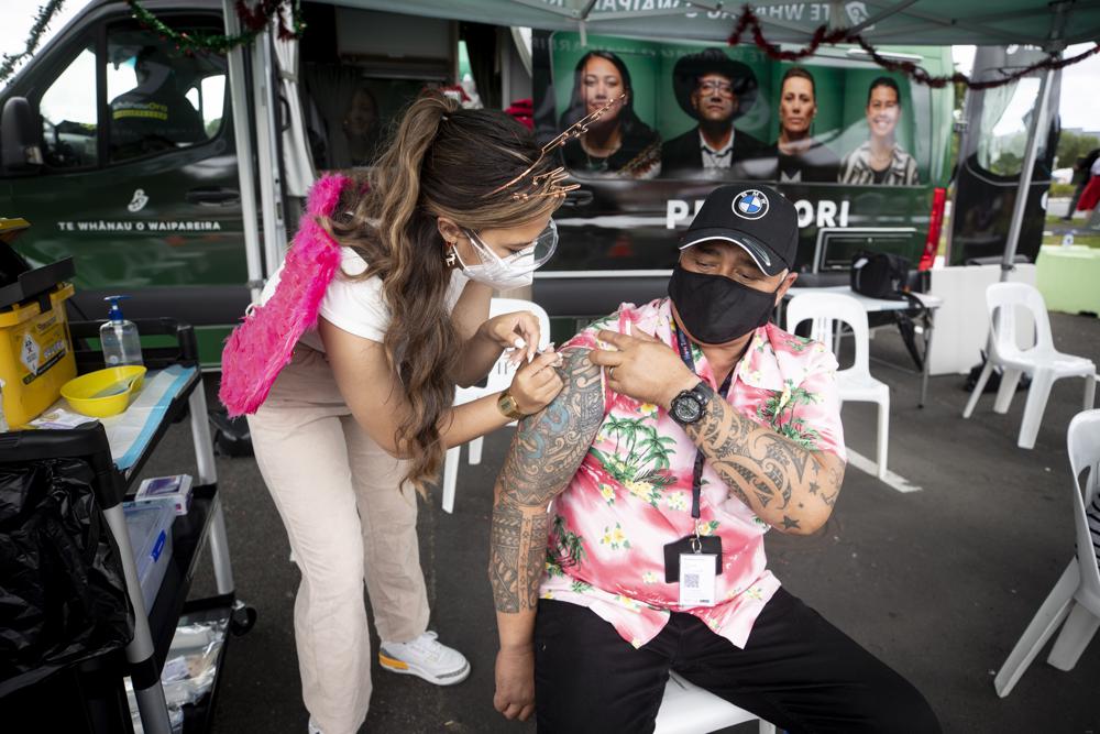 Francis Kumu, right, gets a COVID-19 vaccination Tuesday, Dec. 21, 2021, in Auckland, New Zealand. New Zealand will shorten the gap between second COVID-19 vaccine doses and boosters and push back the phased reopening of its borders in measures announced Tuesday to keep the omicron variant at bay. (Dean Purcell/New Zealand Herald via AP)