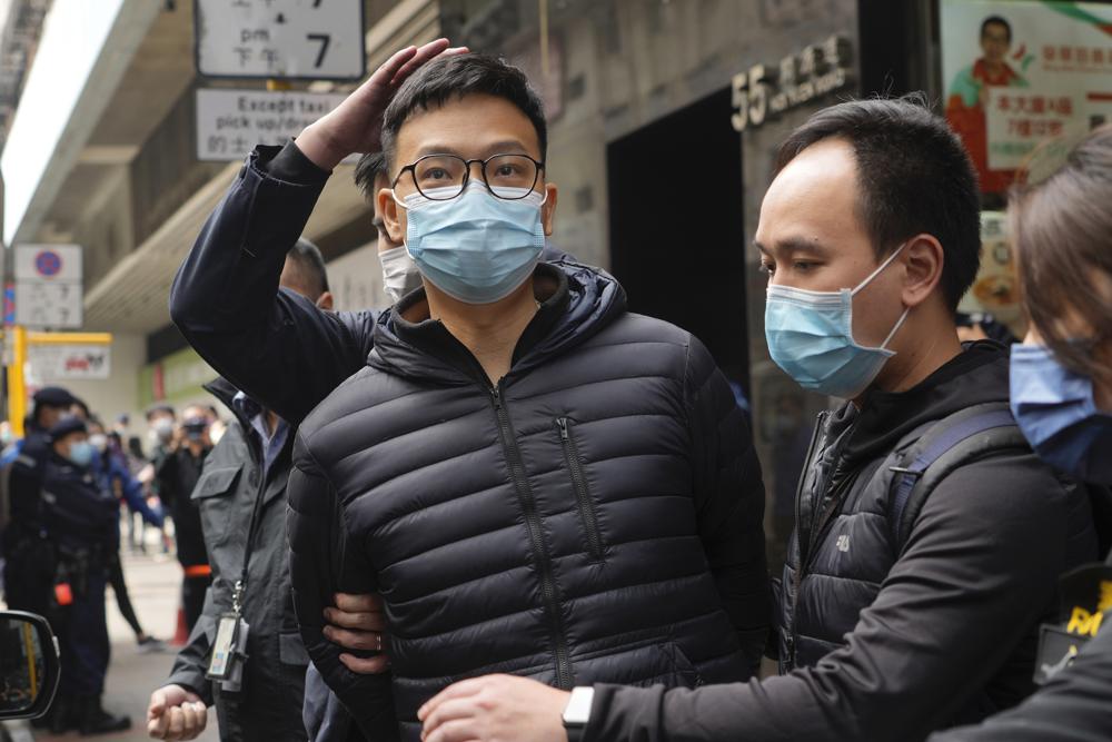 Editor of Stand News Patrick Lam, center, is escorted by police officers into a van after they searched evidence at his office in Hong Kong, Wednesday, Dec. 29, 2021. Hong Kong police raided the office of the online news outlet on Wednesday after arresting several people for conspiracy to publish a seditious publication. (AP Photo/Vincent Yu)