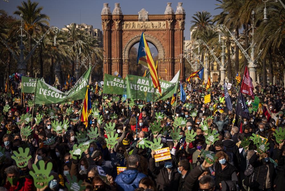 Demonstrators march holding banners and shouting slogans demanding the use of Catalan in schools of Catalonia, in Barcelona, Spain, Saturday, Dec. 18, 2021. Thousands of Catalans took to the streets of Barcelona on Saturday to protest a court decision that mandates a quarter of all classes in schools be taught in Spanish, as opposed to the local Catalan language. Placard reads in Catalan “Now and always, school must be in Catalan”. (AP Photo/Emilio Morenatti)