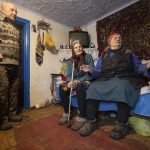 Kateryna Shklyar, right, speaks to The Associated Press as her husband, Dmytro, left, and Halyna Moroka gather near her at her house in the village of Nevelske in eastern Ukraine, on Friday, Dec. 10, 2021. With the bloody conflict between Russia-backed separatists and Ukrainian forces now more than seven years old, there are fears that a buildup of armed forces on Russia’s side of the border could lead to an invasion or the resumption of full-scale hostilities. “We don’t want war!” exclaimed Kateryna Shklyar, who shares the fear with her husband. (AP Photo/Andriy Dubchak)
