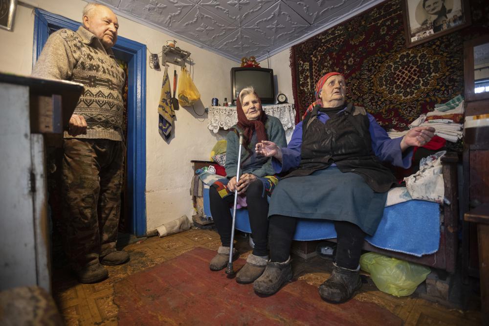 Kateryna Shklyar, right, speaks to The Associated Press as her husband, Dmytro, left, and Halyna Moroka gather near her at her house in the village of Nevelske in eastern Ukraine, on Friday, Dec. 10, 2021. With the bloody conflict between Russia-backed separatists and Ukrainian forces now more than seven years old, there are fears that a buildup of armed forces on Russia’s side of the border could lead to an invasion or the resumption of full-scale hostilities. “We don’t want war!” exclaimed Kateryna Shklyar, who shares the fear with her husband. (AP Photo/Andriy Dubchak)