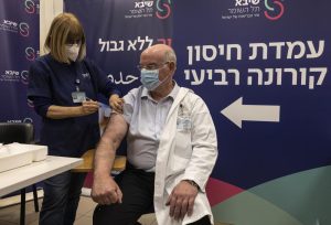 Professor Jacov Lavee receives a fourth dose of Pfizer-BioNTech COVID-19 vaccine, at Sheba Medical Center in Ramat Gan, Israel, Monday, Dec. 27, 2021. Israel began trials of a fourth dose of coronavirus vaccine on Monday with 150 medical personnel who received a booster dose in August in what is believed to be the first study of its kind. (AP Photo/Tsafrir Abayov)