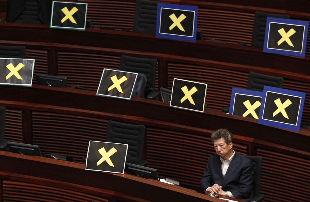 FILE – Pro-democracy lawmaker Ronny Tong sits with placards of yellow crosses placed after the lawmakers walk out of the legislative chamber to protest against Chief Secretary Carrie Lam who unveiled the Beijing-backed election reform package’s details, in Hong Kong on April 22, 2015. Elections for Hong Kong’s Legislative Council on Sunday, Dec. 19, 2021 mark the culmination of Beijing’s campaign to rein in the body that had once kept it from imposing its unrestrained will over the semi-autonomous territory. (AP Photo/Vincent Yu, File)