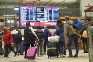 Travellers stand in front of an information board at BER Airport in Berlin, Germany, Saturday, Dec. 18, 2021. Germany’s incoming transport minister is advising people against traveling over Christmas as the country tries to stem a wave of coronavirus infections. (Joerg Carstensen/dpa via AP)