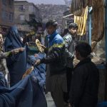 FILE – A man distributes bread to Burka-wearing Afghan women outside a bakery in Kabul, Afghanistan, Thursday, Dec, 2, 2021. Pakistan is rallying Muslim countries to help Afghanistan stave off an economic and humanitarian disaster while also cajoling the neighboring country’s new Taliban rulers into concessions to soften their image abroad. (AP Photo/Petros Giannakouris, File)