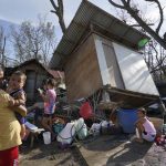 Residents stand amid damaged homes following Typhoon Rai in Talisay, Cebu province, central Philippines on Saturday, Dec. 18, 2021. The strong typhoon engulfed villages in floods that trapped residents on roofs, toppled trees and knocked out power in southern and central island provinces, where more than 300,000 villagers had fled to safety before the onslaught, officials said. (AP Photo/Jay Labra)