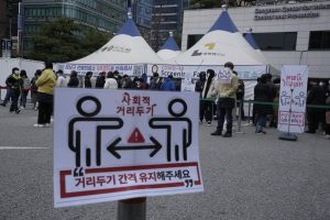 Social distancing signs on precautions against the coronavirus are displayed as people queue in line for the coronavirus testing at a public health center in Seoul, South Korea, Thursday, Dec. 9, 2021. New coronavirus infections in South Korea have been rising and breaking records daily. There were long lines at testing stations after they exceeded 7,000 for the first time on Wednesday since the start of the pandemic. More than 5,600 of the new 7,175 cases were reported in Seoul and the nearby metropolitan region. (AP Photo/Ahn Young-joon)