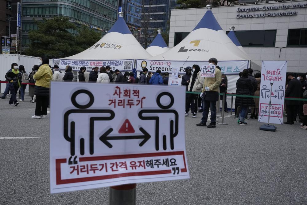 Social distancing signs on precautions against the coronavirus are displayed as people queue in line for the coronavirus testing at a public health center in Seoul, South Korea, Thursday, Dec. 9, 2021. New coronavirus infections in South Korea have been rising and breaking records daily. There were long lines at testing stations after they exceeded 7,000 for the first time on Wednesday since the start of the pandemic. More than 5,600 of the new 7,175 cases were reported in Seoul and the nearby metropolitan region. (AP Photo/Ahn Young-joon)