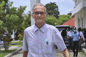 FILE – Richard Daschbach, a former missionary from Pennsylvania, is escorted by a police officer upon his arrival for a trial at a courthouse in Oecusse, East Timor on Feb. 23, 2021. The defrocked American priest accused of sexually abusing orphaned and disadvantaged young girls under his care in East Timor was found guilty Tuesday, Dec. 21, 2021 and sentenced to 12 years in prison, in the first case of its kind in the staunchly Catholic nation. (AP Photo/Raimundos Oki, File)