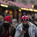 People walk past a Christmas market in Trafalgar Square in London, Wednesday, Dec. 22, 2021. British Prime Minister Boris Johnson said on Monday that his government reserves the “possibility of taking further action” to protect public health as Omicron spreads across the country. (AP Photo/Frank Augstein)