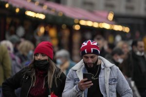 People walk past a Christmas market in Trafalgar Square in London, Wednesday, Dec. 22, 2021. British Prime Minister Boris Johnson said on Monday that his government reserves the “possibility of taking further action” to protect public health as Omicron spreads across the country. (AP Photo/Frank Augstein)
